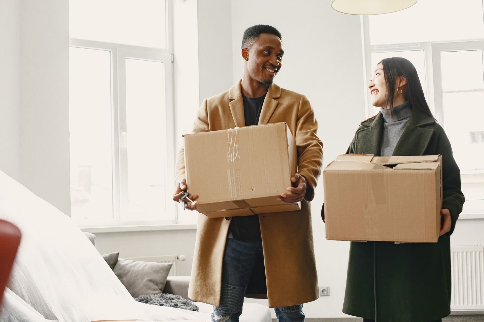 Smiling couple carrying moving boxes into their new home